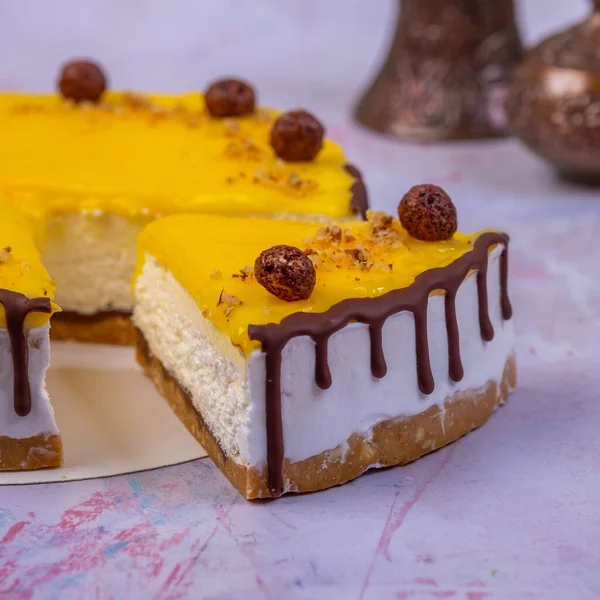 배경에 초콜릿 초콜릿 공으로 장식된 노란색 표면으로 장식된 케이크 조각을 — 스톡 사진