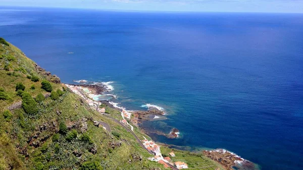 在葡萄牙亚速尔的一个阳光明媚的日子里 蓝色的大海和山下的房屋映照在海岸上 — 图库照片