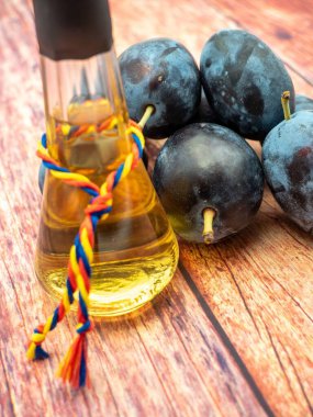 Ahşap masada erikli erik brendisinin dikey görüntüsü.