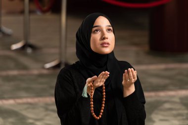 Camide namaz kılarken elini kaldıran beyaz Müslüman bir kadın.