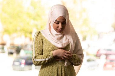 Bej tesettürlü Müslüman bir kadın ve Allah için dua eden geleneksel giysiler.