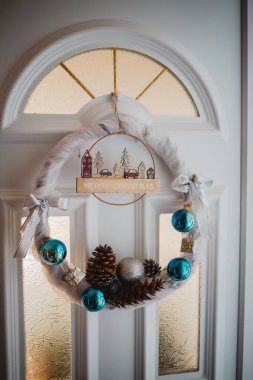 Beyaz kapılı bir Noel çelenginin dikey görüntüsü.