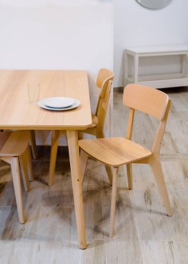 Dikey beyaz tabaklar ve tahta bir masanın üzerinde boş bir bardak.