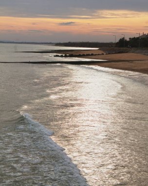 Gün batımında huzurlu bir kumsalın dikey görüntüsü.