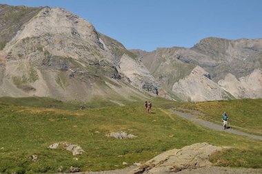 Katalan Pireneleri 'ni keşfeden bir grup turist ve yeşil tarlaların üzerinde uzanan yüksek kayalık dağlar.