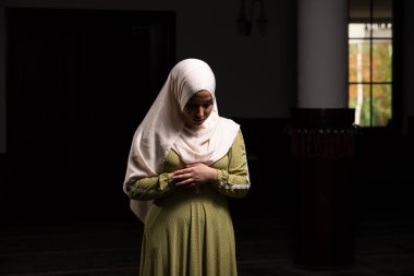 Camide huzur içinde dua eden muhteşem bir Müslüman kadının portresi.