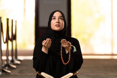 Camide namaz kılarken elini kaldıran beyaz Müslüman bir kadın.