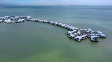 Denizin ortasındaki bir iskeledeki binaların kuş bakışı görüntüsü.