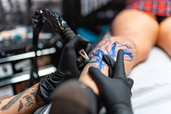 Zbliżenie Tatuażysty Robiącego Tatuaż Kobiecej Nodze Salonie — Zdjęcie stockowe