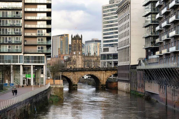曼彻斯特市中心的伊尔韦尔河和曼彻斯特大教堂 人们沿着汹涌的水路走着 — 图库照片