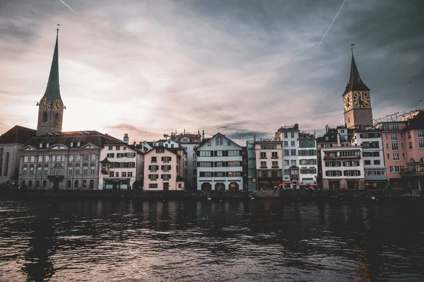 stock image The waterfront of Limmat river with St. Peter's and Fraumunster Church at the sunset in Zurich, Switzerland