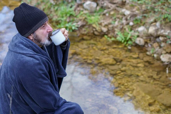 Vousatý Muž Přikrytý Pokrývkou Popíjející Kávu Břehu Řeky — Stock fotografie