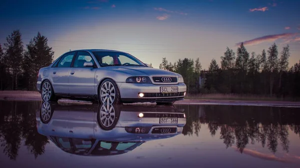 Ένα Audi Και Αντανάκλασή Του Ένα Υγρό Δρόμο Στο Ηλιοβασίλεμα — Φωτογραφία Αρχείου