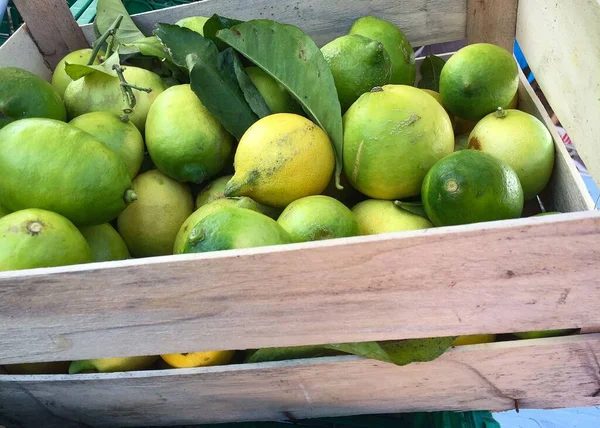 緑と黄色のレモンで満たされた市場からの木製の箱 — ストック写真