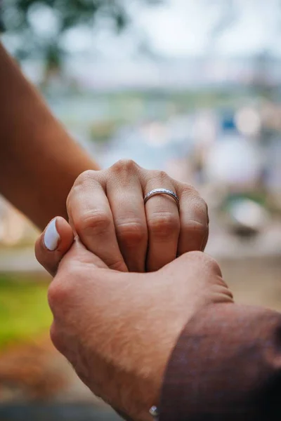 その上に結婚指輪を持つ女性の手を保持する男性の手の閉鎖 ぼやけた背景 — ストック写真