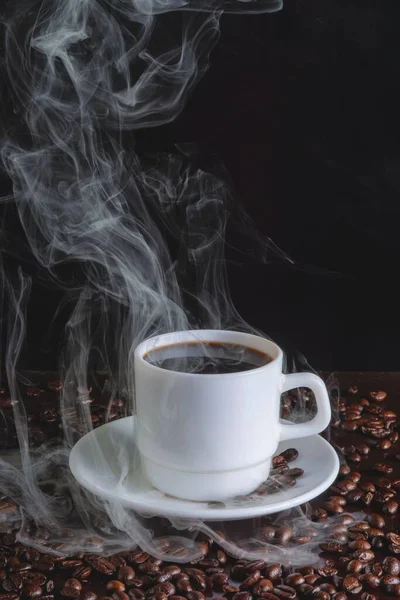 Вертикальный Снимок Чашки Горячего Кофе Окружении Кофейных Зерен Изолированных Черном — стоковое фото