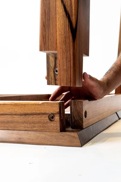 A vertical close-up of a male hand assembling wooden home furniture