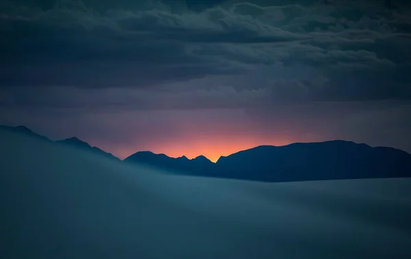 Güneşin Batışında Gri Bulutlu Gökyüzünün Altında Dağların Ufuk Çizgisi — Stok fotoğraf