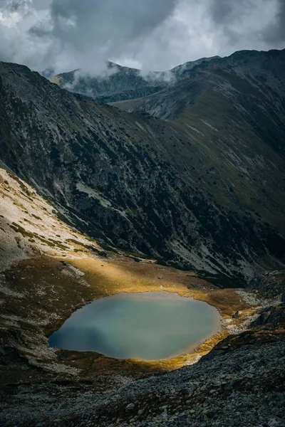 Vertikální Malé Jezero Obklopeno Velkými Horami Zamračený Den Během Dne — Stock fotografie
