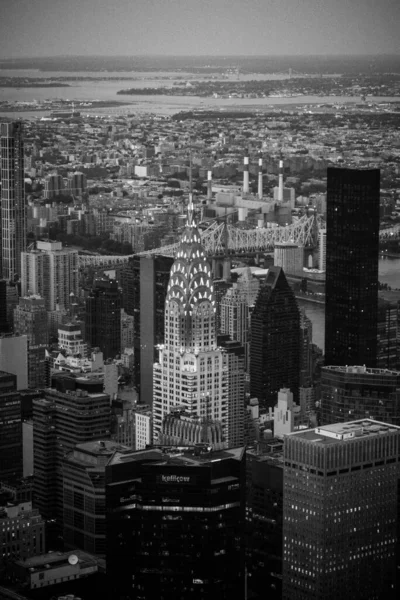 Pionowe Ujęcie Iluminowanego Budynku Chryslera Otoczone Wieżowcami Nocy Skali Szarości — Zdjęcie stockowe