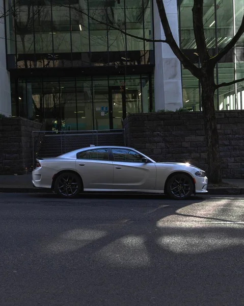Pionowe Ujęcie Srebrnego Samochodu Zaparkowanego Przed Wejściem Budynku — Zdjęcie stockowe