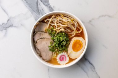 Lezzetli bir ramen kasesi, biftek ve mermer masada servis edilen bir yumurta.