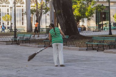 Güneşli bir günde Özgürlük Parkını temizleyen bir kadın, Matanzas, Küba