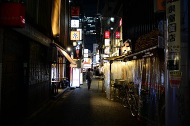 Tokyo 'da dar bir sokak, gece ışıklarıyla aydınlanıyor.