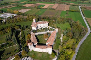 Güneşli bir günde, İtalya 'daki Castello Villalta şatosunun çimen tarlasıyla çevrili hava manzarası.