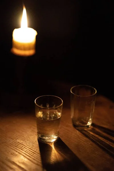 一支垂直的玻璃杯靠近点燃的蜡烛 — 图库照片