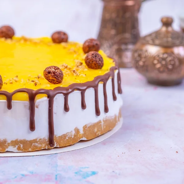 チョコレートクリームとチョコレートボールで装飾された黄色の表面を持つチーズケーキのクローズアップぼやけた背景に — ストック写真