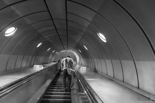 Graustufen Eines Mannes Der Auf Einer Bahn Rolltreppe Aufsteigt — Stockfoto