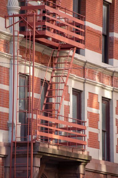 A vertical shot of a fire escape staircase of a red brick building in New York, United States.