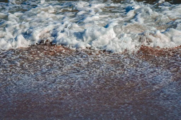 昼間に砂浜を転がす海の泡の波の閉鎖 — ストック写真