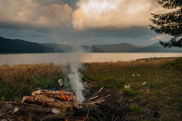 輝く夕日の中 湖のそばに優しい炎の小さなキャンプファイヤー — ストック写真