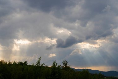Bulutlu gökyüzü, güneş ışığı dağların üzerindeki bulutları delip geçiyor..