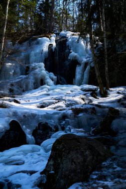 Donmuş şelale karla ve buzlu kayalarla çevrili.
