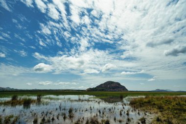 Sakin bir su kütlesinin üzerindeki bulutlarla manzara.