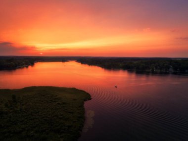Gün batımı sakin nehir manzarasına yansıyor