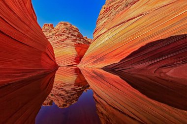 Renkli kaya oluşumları ve su içeren çarpıcı bir manzara..