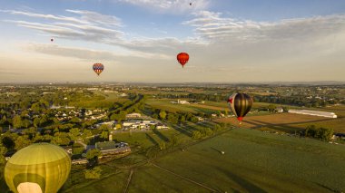 Dev balonlar içsel ışıkla parıldıyor, temiz, sıcak sabah havasına yükselmeyi bekliyorlar..