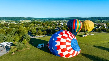 Sepetlerin siluetleri gökyüzüne doğru yükselen büyük renkli kumaşların altında görünür..