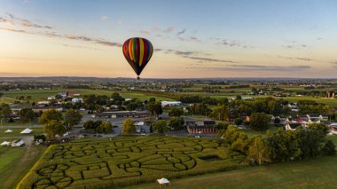 Sepetlerin siluetleri gökyüzüne doğru yükselen büyük renkli kumaşların altında görünür..