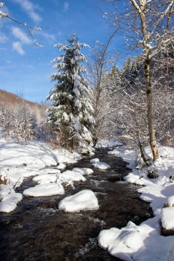 İçinden bir nehir akan karlı bir arazi..