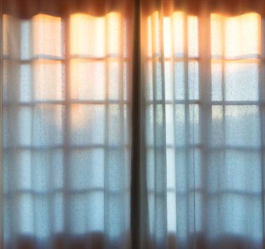 Sunlight shining through sheer curtains in window