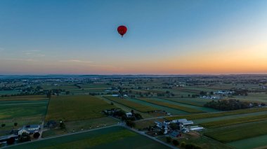Sepetlerin siluetleri gökyüzüne doğru yükselen büyük renkli kumaşların altında görünür..