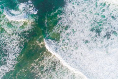 Kıyı üzerindeki köpüklü dalgaların hava aracı görüntüsü, turkuaz su