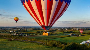 Birden fazla parlak desenli balon, puslu ve düşük ışıklı gökyüzüne karşı yükselmek için hazırlanır..