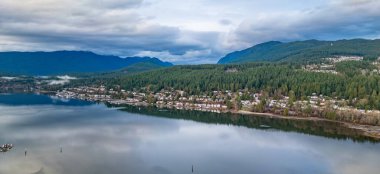 Okyanus kıyısındaki yerleşim yerleri ve arka planda dağlar. Port Moody, Vancouver, BC, Kanada.