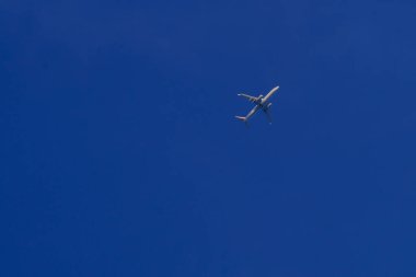 Açık mavi gökyüzünde uçan bir ticari uçak..